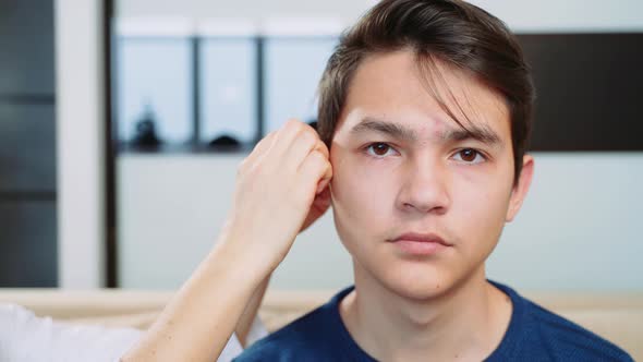 Woman doctor puts on hearing aid boy teenager