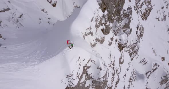 Aerial drone view of a skier skiing down a steep snow covered mountain.