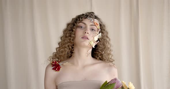 Attractive Woman with Flowers on Face Pose in Studio