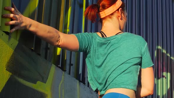 A young woman stretching before working out in urban environment.
