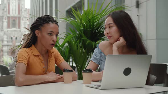 Two Beautiful Girls with Laptop in Coffee House