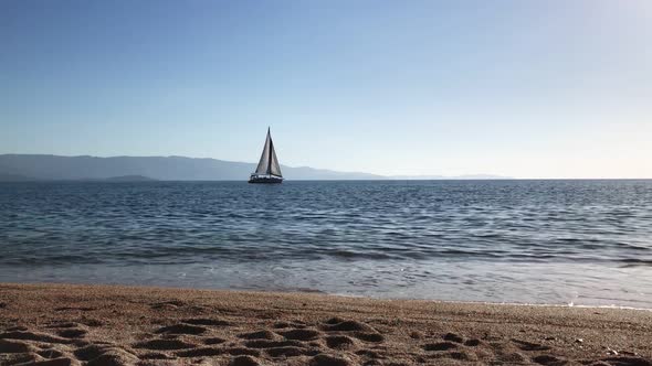 A View From the Shore To a Sailing Yacht Sailing in the Sea on a Sunny Day