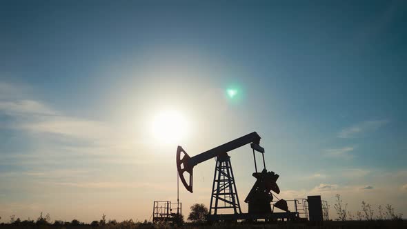 Silhouette of Working Oil Pump From Oil Field at Sunset. The Industrial Equipment.