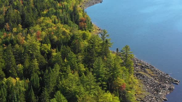 Aerial footage of remote lake in northern Maine VERTIGO ORBIT around wooded rocky shoreline