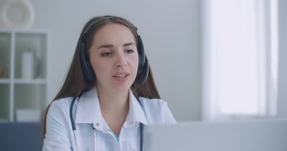 Hardworking Indian Female Doctor Doing Video Call on Laptop in Hospital. Smiling Young Female Doctor