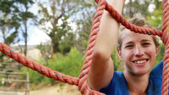 Fit woman climbing a net during obstacle course