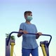 A teenage boy in a medical mask plays sports on exercise machines - VideoHive Item for Sale