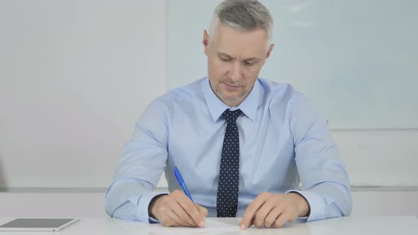 Senior Businessman Writing Letter at Work, Paperwork