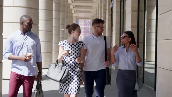 Slider Shot of Group of Diverse Coworkers Walk Outside Office Building Hold Paper Cup and Talk
