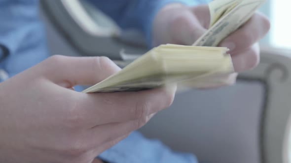 Close Up Hands of the Young Man in Blue Shirt Sitting in the Armchair Counting Money