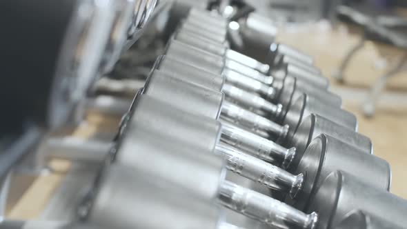 Row of Hand Weights Lying on Stand in Gym As Unrecognizable Sportsman Taking One. Caucasian Man