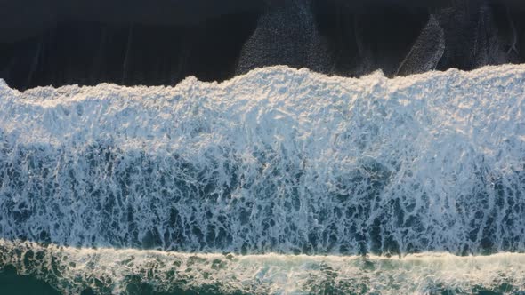 Aerial view of ocean wave splashes into the sand coast