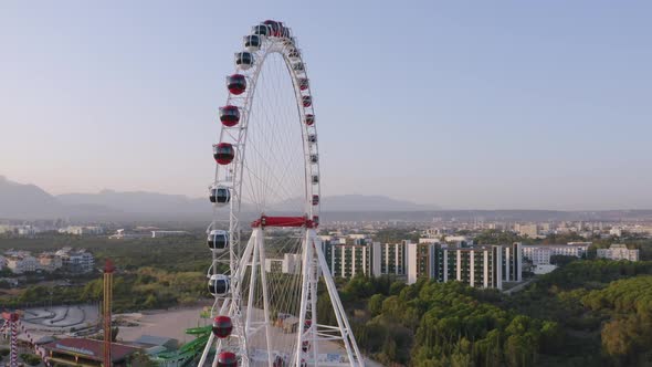 Ferris Wheel on the Background of Modern European City and Mountains