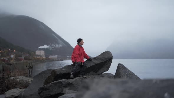 Lone Hiker Sitting On Rock By Fjord
