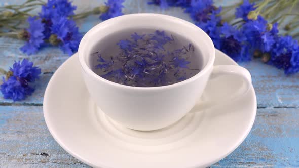 Brewing a tisanes from knapweeds flowers in white cup.