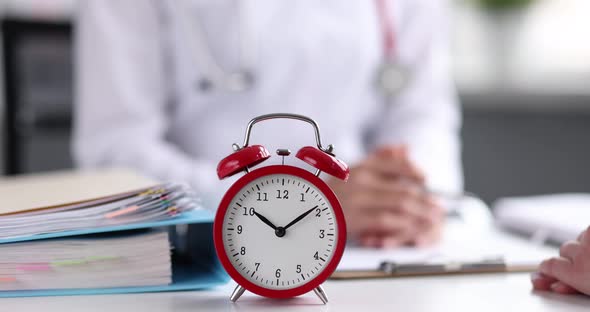 Two Business People Communicate in Office on Table is Alarm Clock Closeup