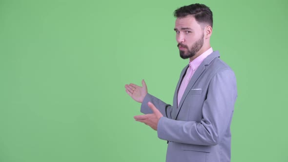 Happy Young Bearded Businessman Presenting To the Back