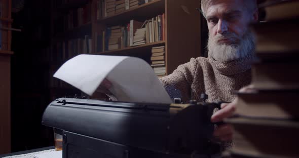 Ernest Hemingway is putting a sheet of paper into the typewriter, 4k