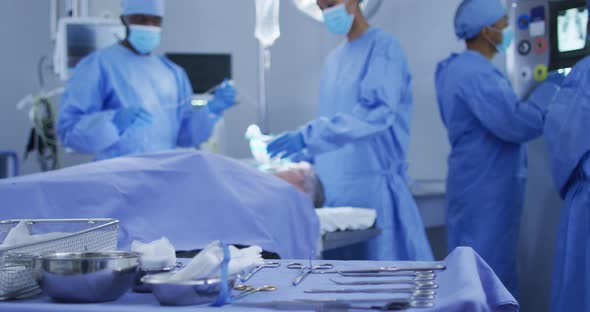 Mixed race surgeons wearing protective clothing putting patient to sleep in operating theatre