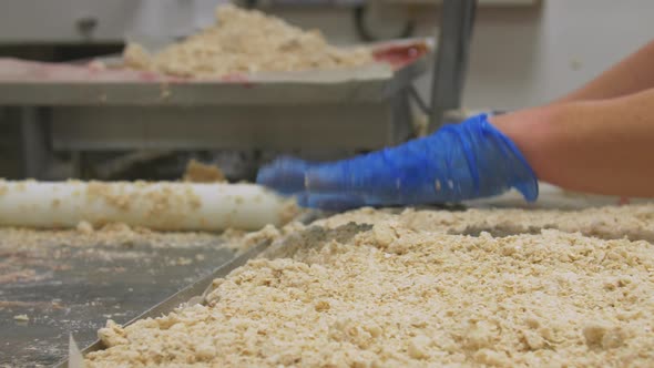 Pan from left to right of workers preparing crumble cake so the topping covers the tray evenly