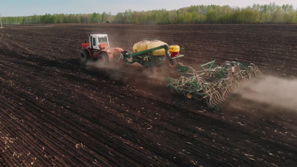 Process of Sowing Cereals and Other Crops. Drone View of a Modern Tractor Working on a Huge Field