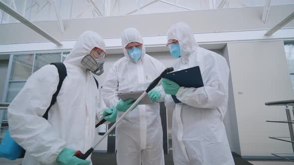 Covid-19 Coronavirus Epidemic. Three People in Protective Suits in Office To Disinfect