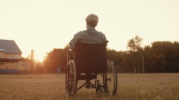 Disabled Person Woman is Sitting Wheelchair in Middle of Field Background Sunset and Waving Her