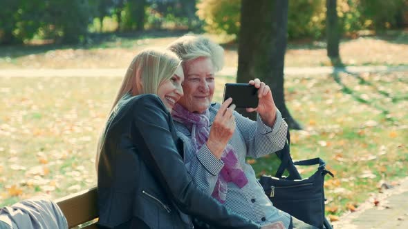 Zoom Shot of Young and Old Women Making Selfie on Smartphone in Autumn Time in a Beautiful Park