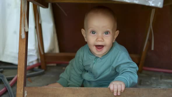 Happy Smiling Caucasian Baby Toddler Kid Sitting Under Chair Table Outside Yard