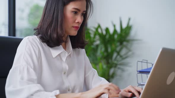 Asian young business woman sit on table work on a computer in the office with a new normal lifestyle