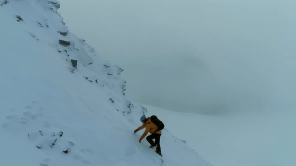 Mountaineer Using a Pick to Climb a Snowy Mountain