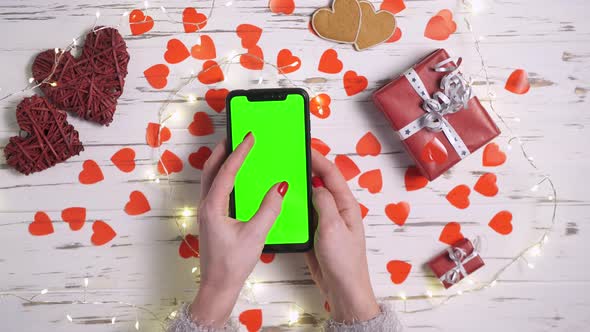 Valentine's Day a Woman Uses a Smartphone with a Green Screen Closeup Top View