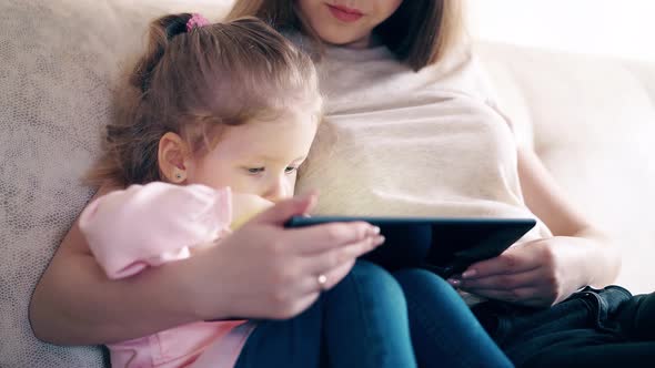 Mother and Sweet Daughter Are Sitting on the Couch