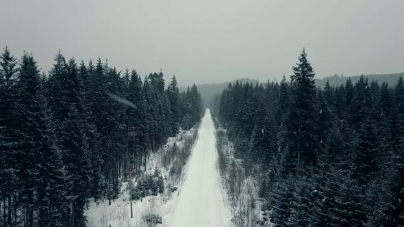 Aerial View From Drone on Car Driving Through Winter Snow Covered Forest