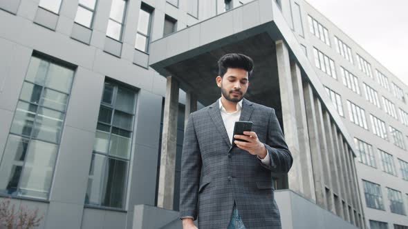 CloseUp of Attractive Young Businessman Using Smartphone and Smiles