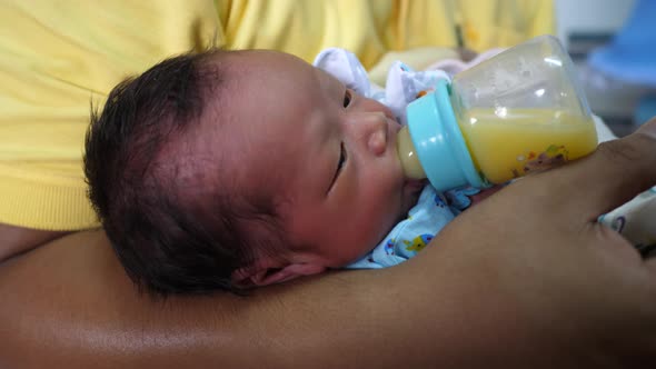 The newborn is eating breast milk from a bottle, slow-motion shot