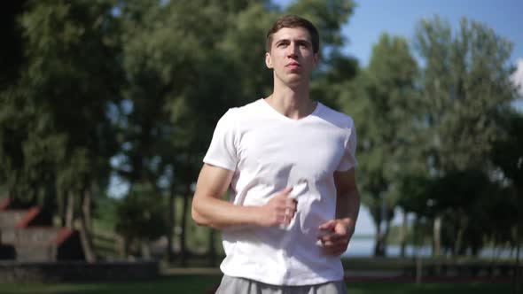Front View Positive Confident Sportsman Running Outdoors in Park Leaving