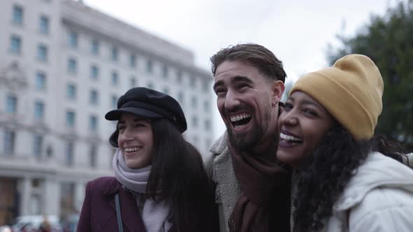 Two Women and One Man United Laughing Together and Having Fun Outdoors