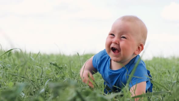 Baby Sitting Crawling on Green Grass and Smiling Broadly Excited Cute Little Caucasian Child
