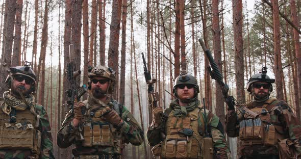 Squad of Fully Equipped Soldiers in Camouflage Stand in Dense Pine Forest Reconnaissance Military