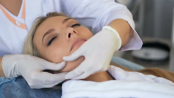 Beautiful Woman Enjoying of Facial Massage in Beauty Salon