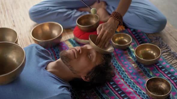 Superslowmotion Shot of a Woman Master of Asian Sacred Medicine Performs Tibetan Bowls Healing