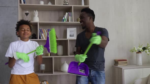 Young Dad and Son Having Fun with Cleaning Tools in Hands and Laughing Standing in Room Spbi