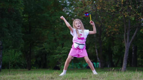 Little girl with colorful pinwheel in park.