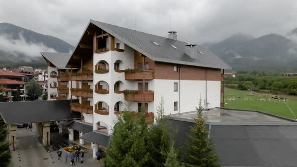 Aerial drone flying over a hotel in Bansko, Bulgaria, revealing mountain with clouds and fog