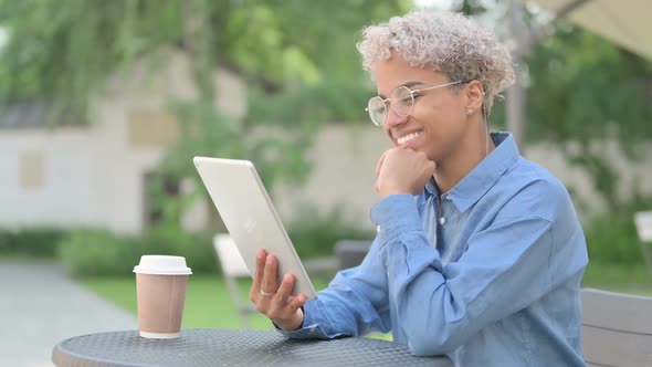 Young African Woman Making Video Chat on Tablet in Outdoor Cafe