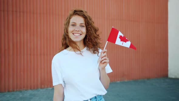 Slow Motion of Happy Female Student Holding Canadian Flag Outdoors Smiling