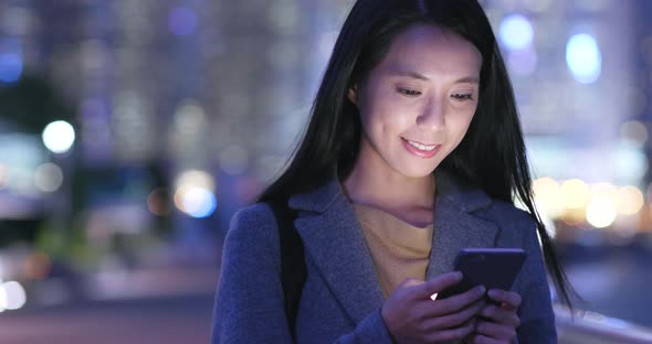 Woman look at mobile phone in city at night