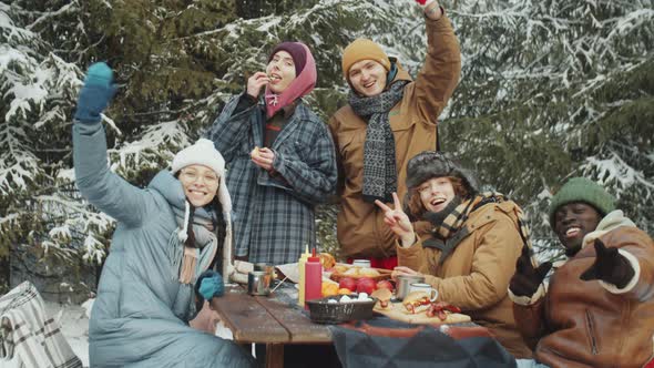 Portrait of Happy Friends at Camp Table in Winter Forest