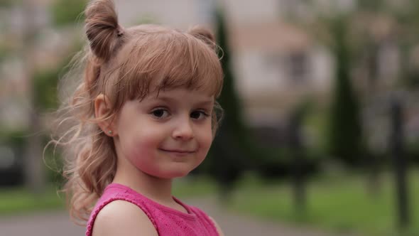 Little Child Girl Against the Blurred City Street Background. Cheerful, Positive Emotions, Smile